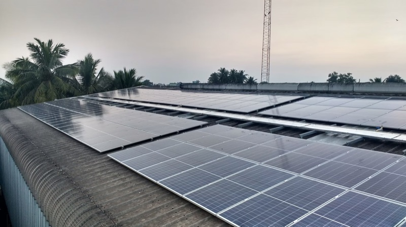 Rooftop solar array at a spices and food processing plant, Melmudalambedu, with coconut palms beyond